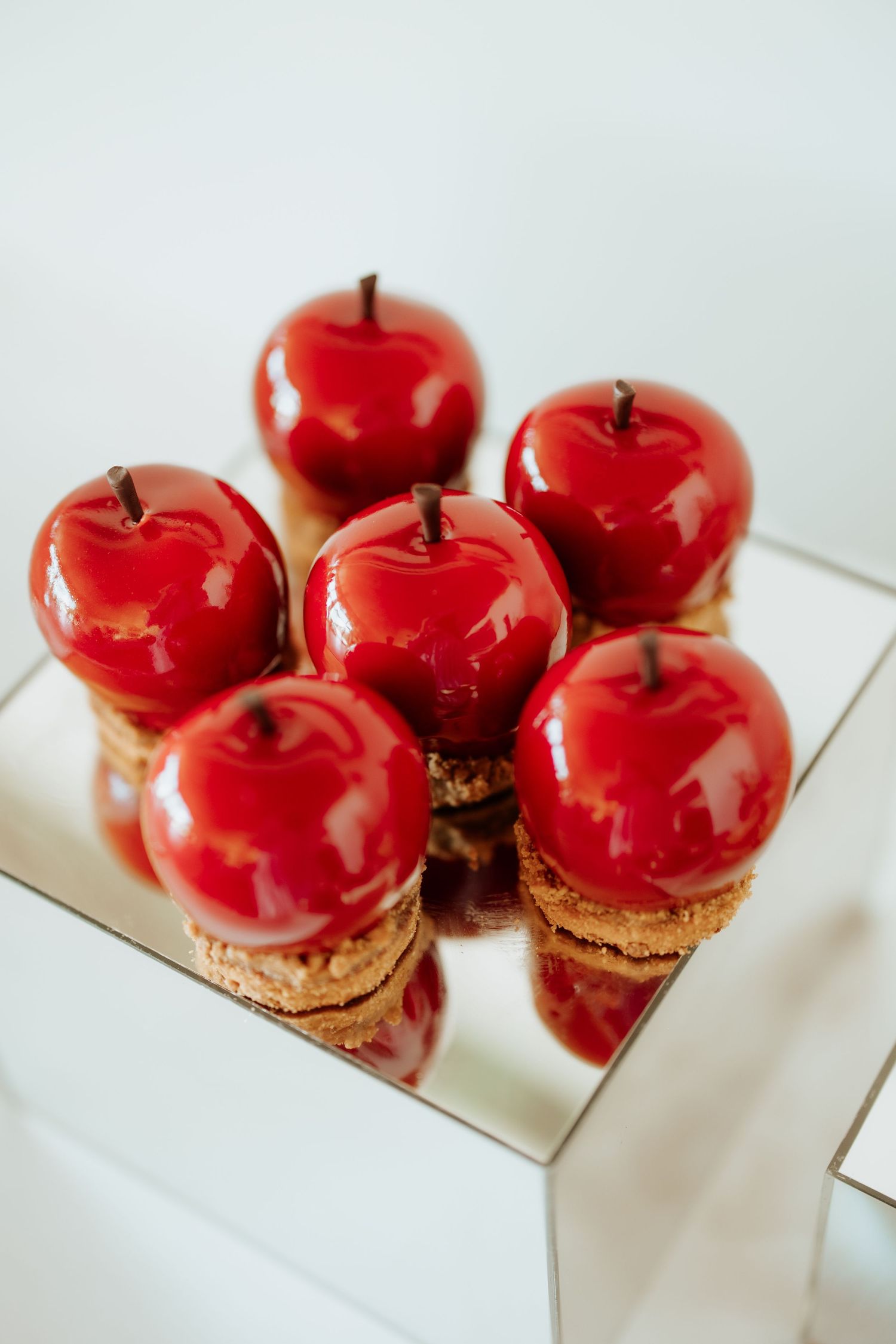 Bright red candied apples displayed on a mirrored surface.