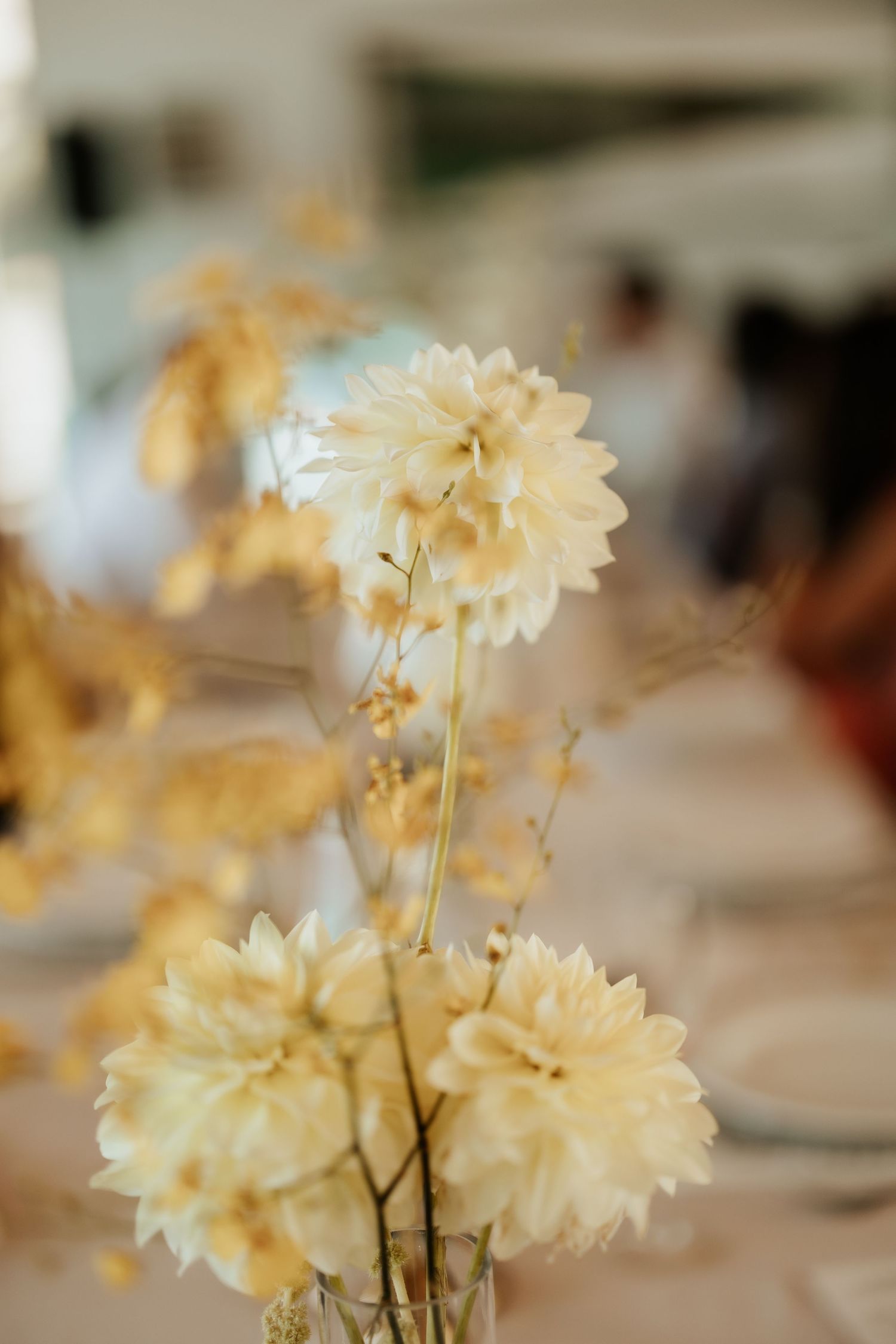 Soft yellow dahlia flowers in delicate wedding table centerpiece arrangement.
