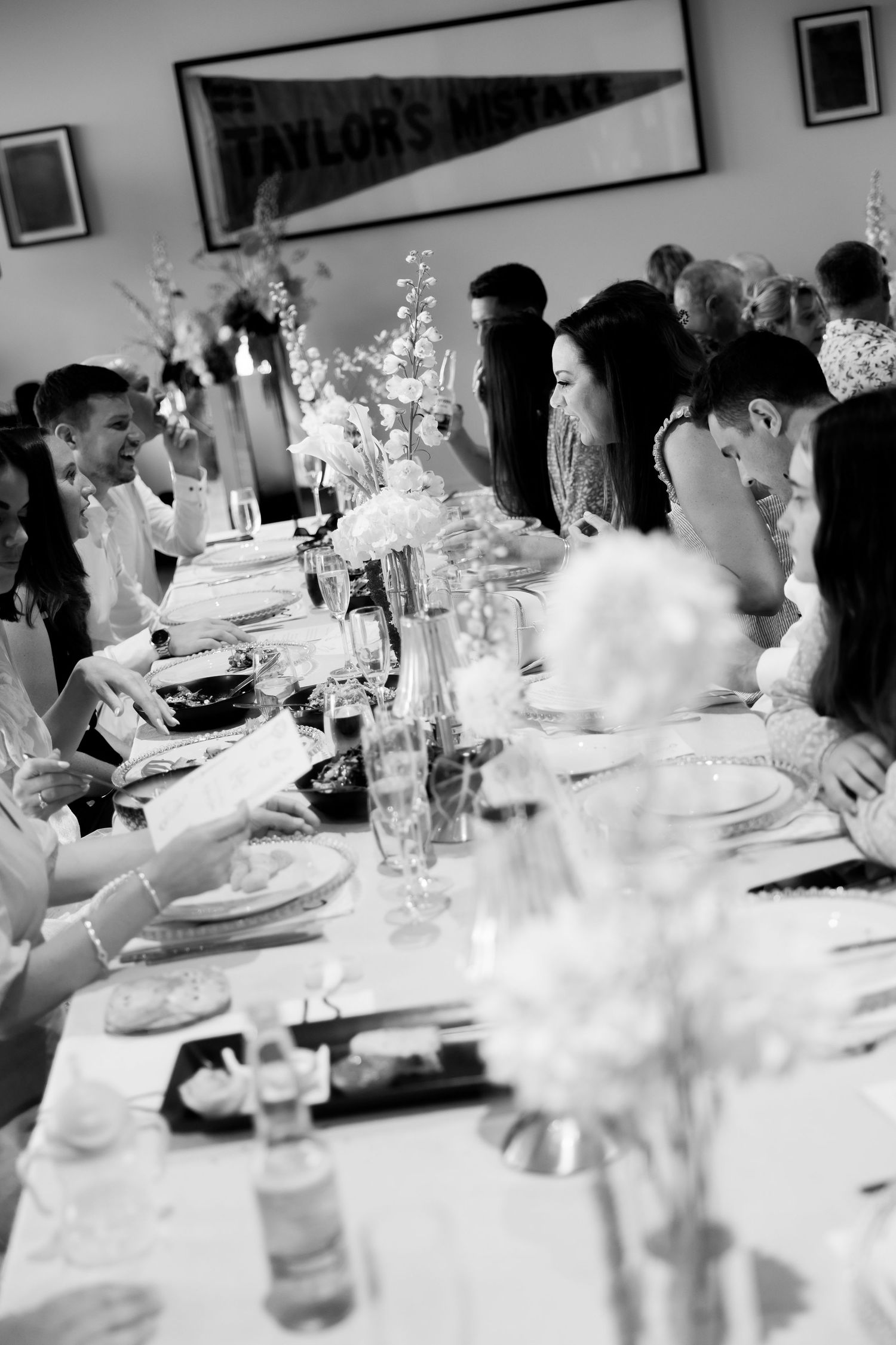 An elegant wedding reception table setting with white floral centerpieces and place settings.