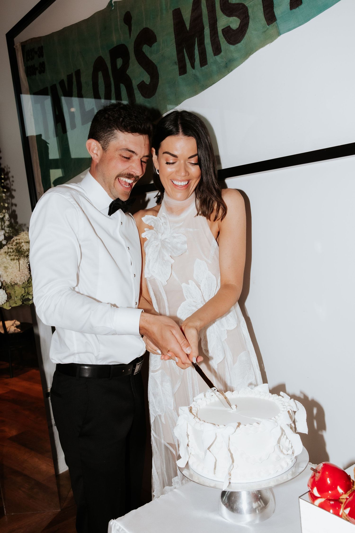 Wedding couple cuts their white wedding cake together at reception.