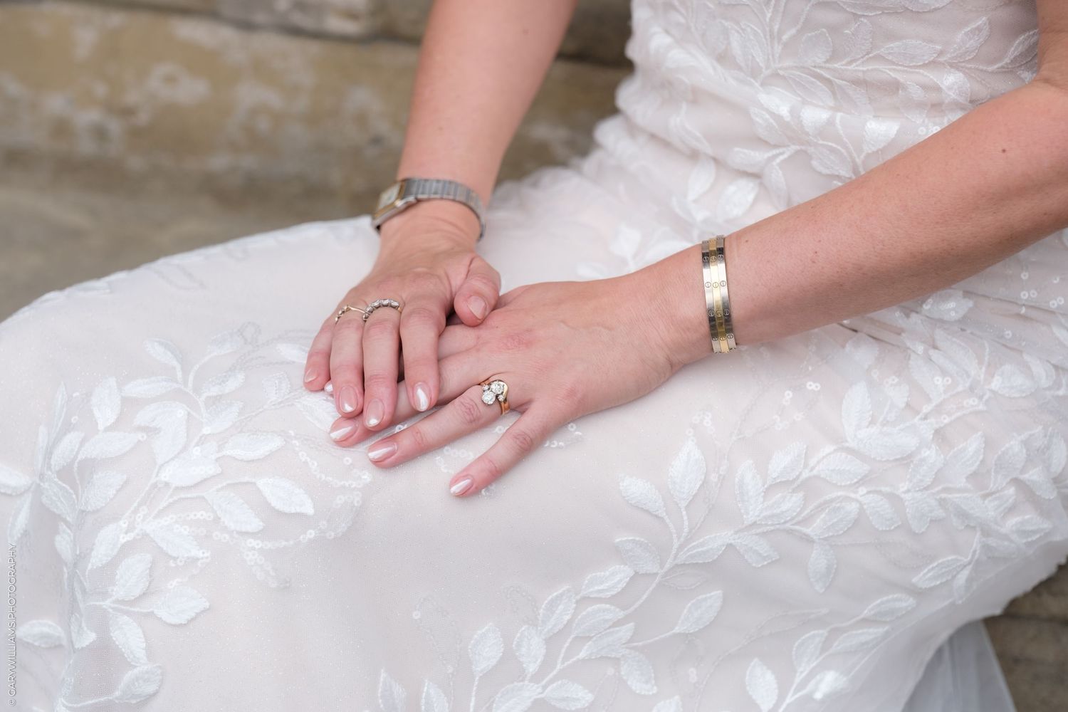 Hands smoothing out layers of delicate white tulle fabric on a light colored surface.