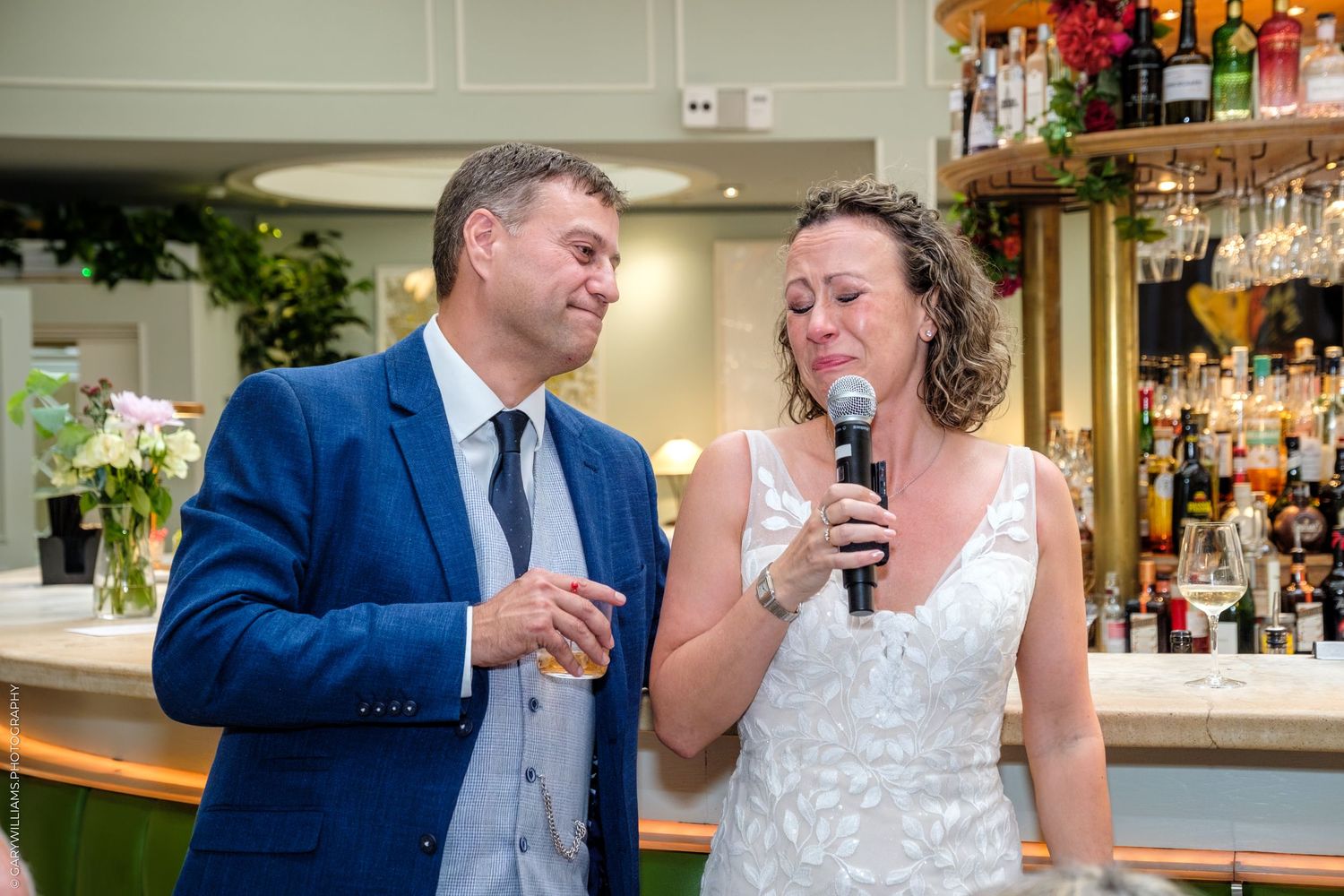 Bride and groom share joyful moments in a bar setting with warm lighting and festive decorations.