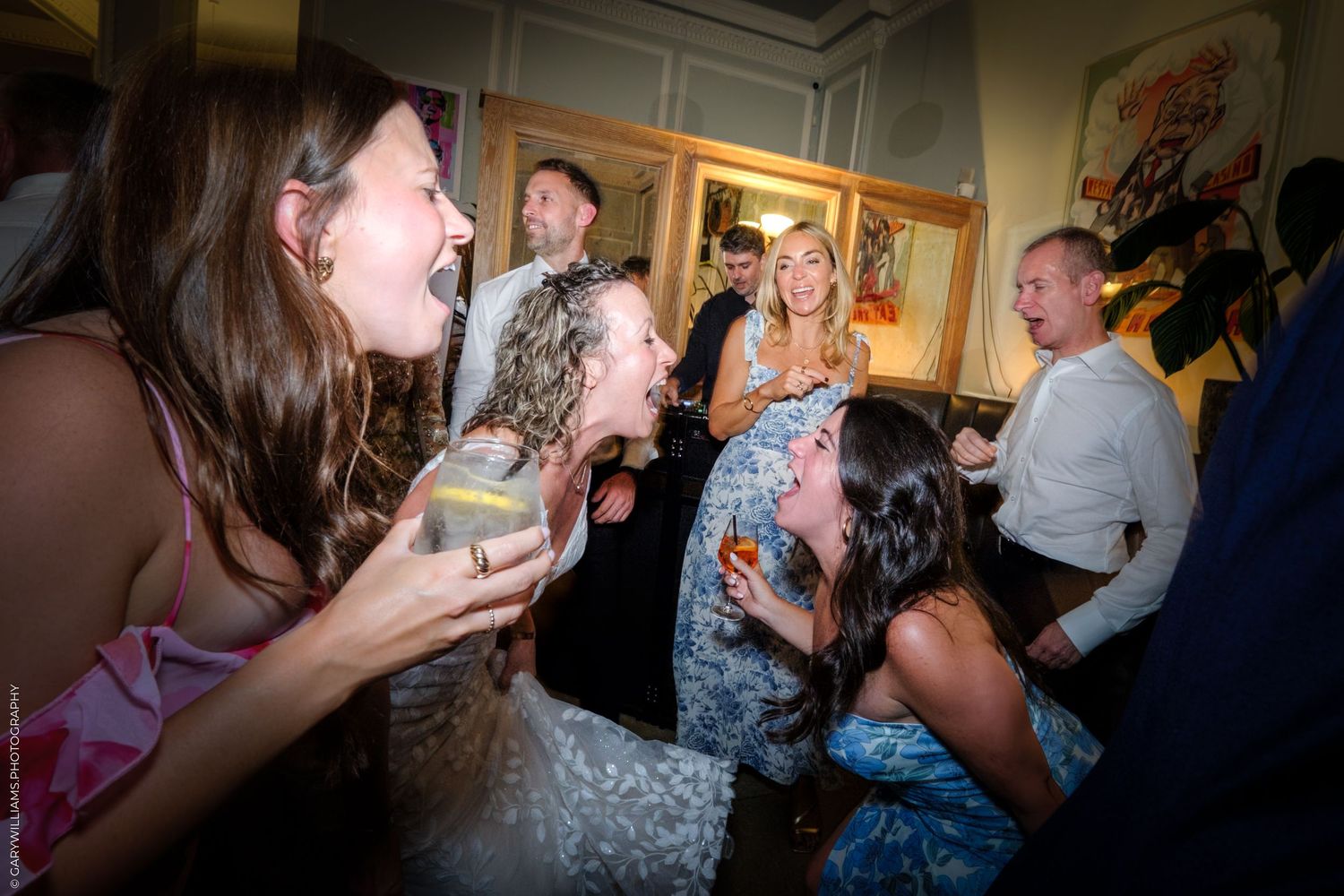 People laughing and socializing at an indoor party gathering in a bright room.