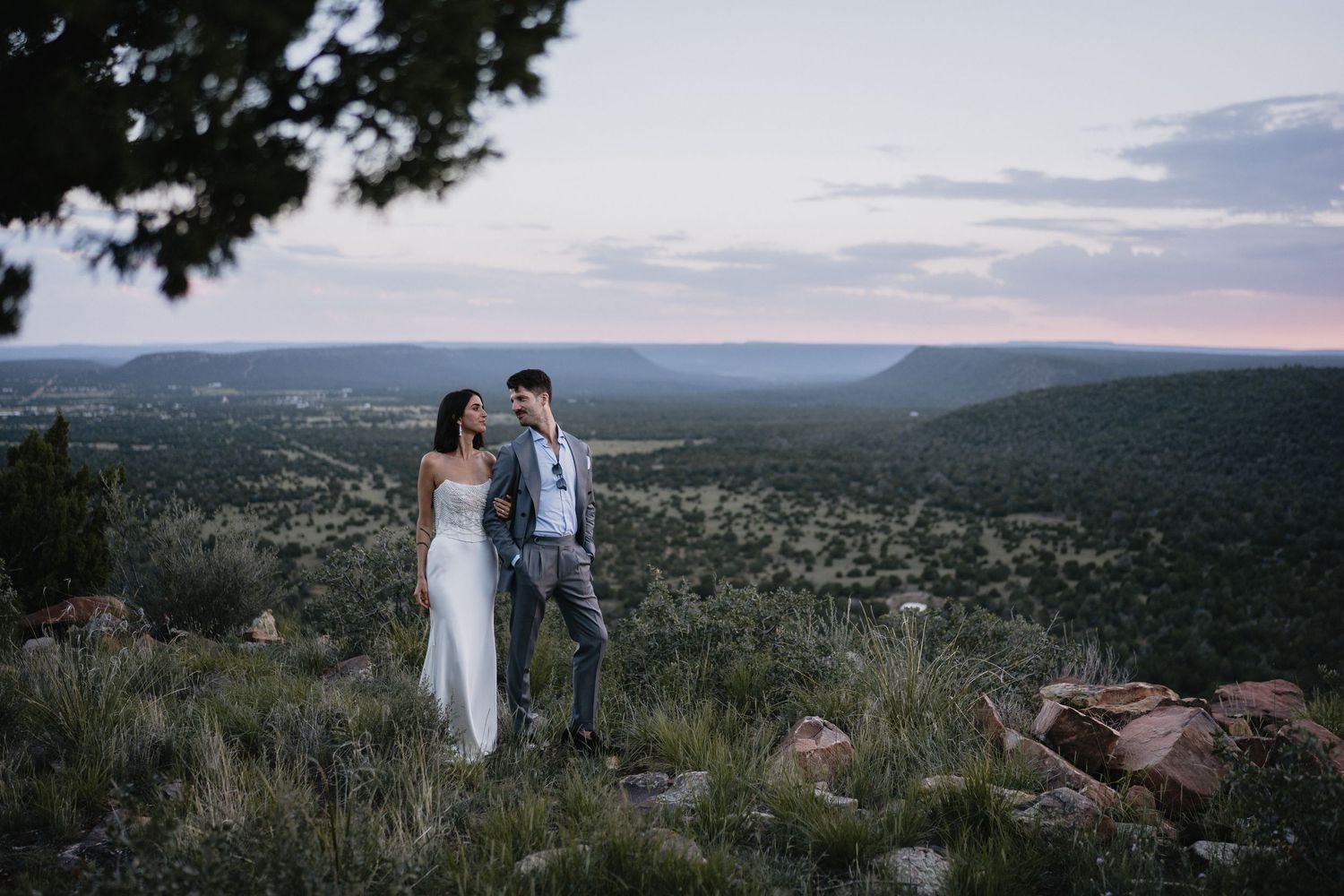 Bride and groom share a romantic moment on a rocky hilltop at sunset in New Mexico.cinematic wedding photographer new mexico