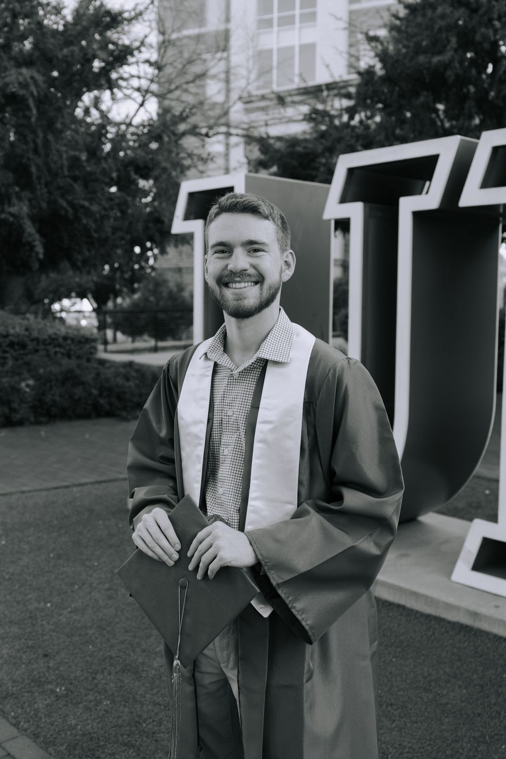 Black and white graduation photos taken outdoors with brick buildings in background.