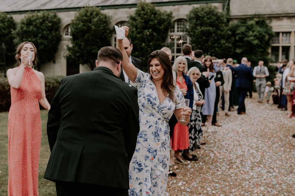 Guest pouring confetti over groom's head outdoors while smiling at a Melton Mowbray wedding