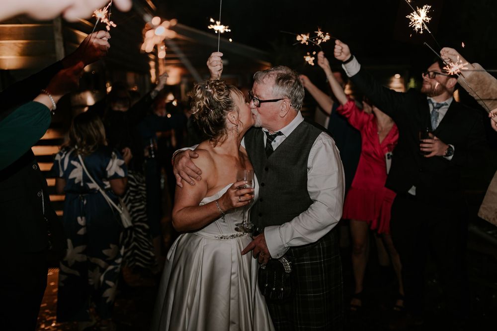 Couple kissing surrounded by sparklers on dimly lit dance floor, Melton Mowbray wedding.