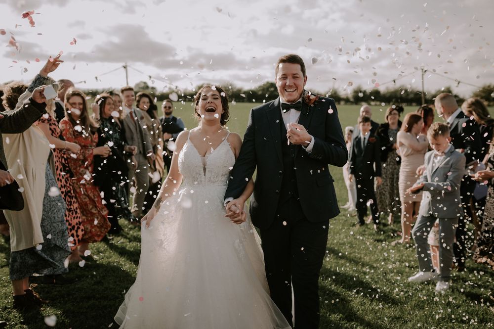 Wedding celebration with confetti being thrown over the couple in a sunny outdoor setting. Melton Mowbray wedding