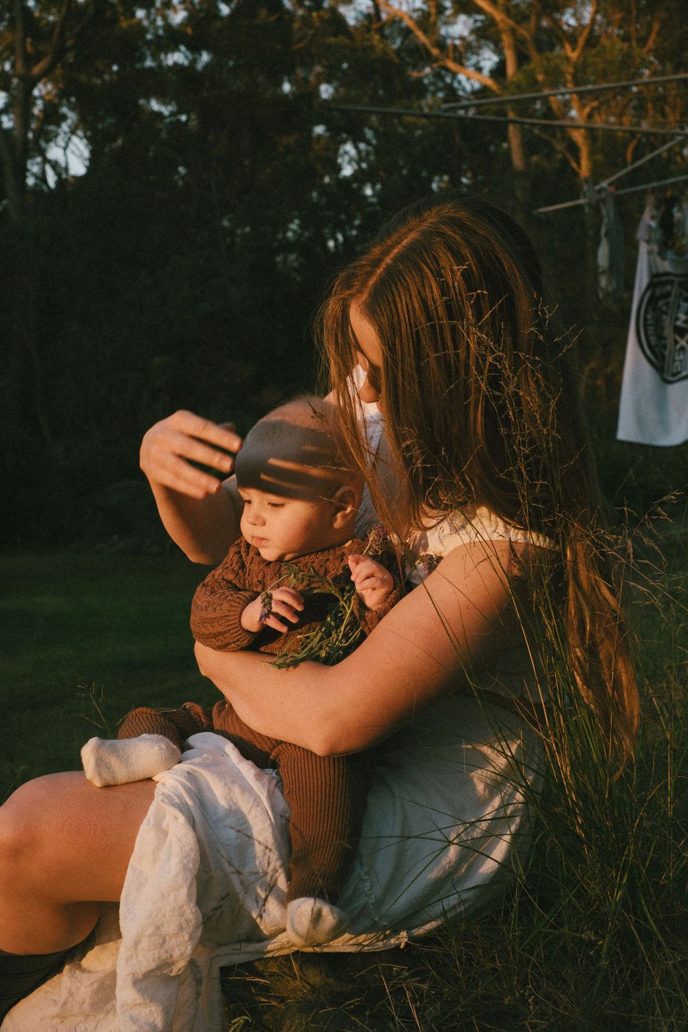 Intimate outdoor moment between parent and child during sunset among tall grass.