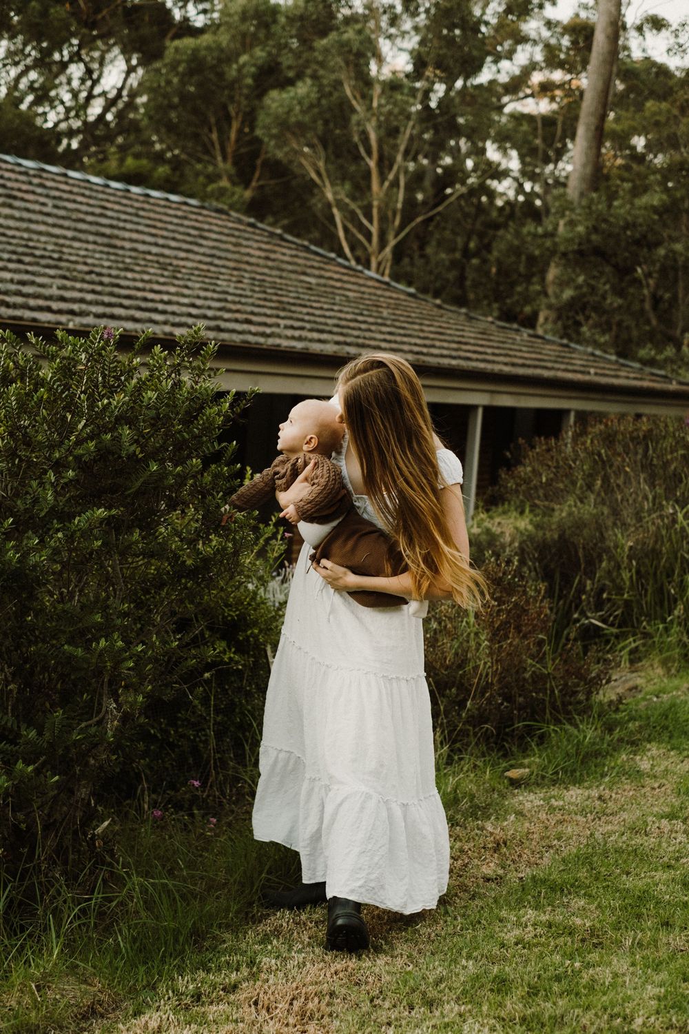 White dress flowing in gentle movement against lush garden background.
