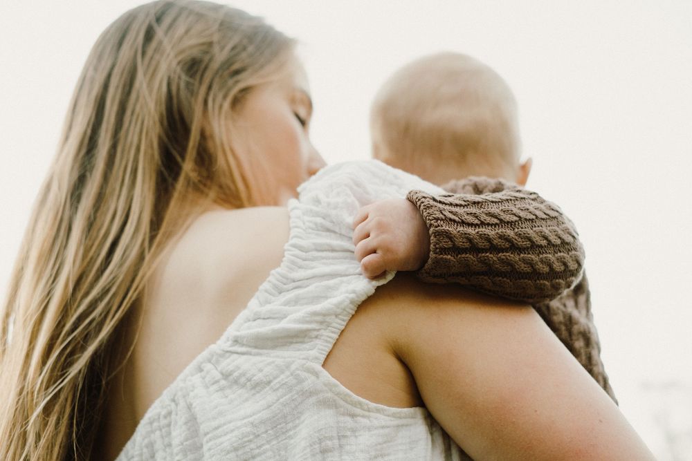 Soft lighting illuminates tender embrace in white and brown clothing.