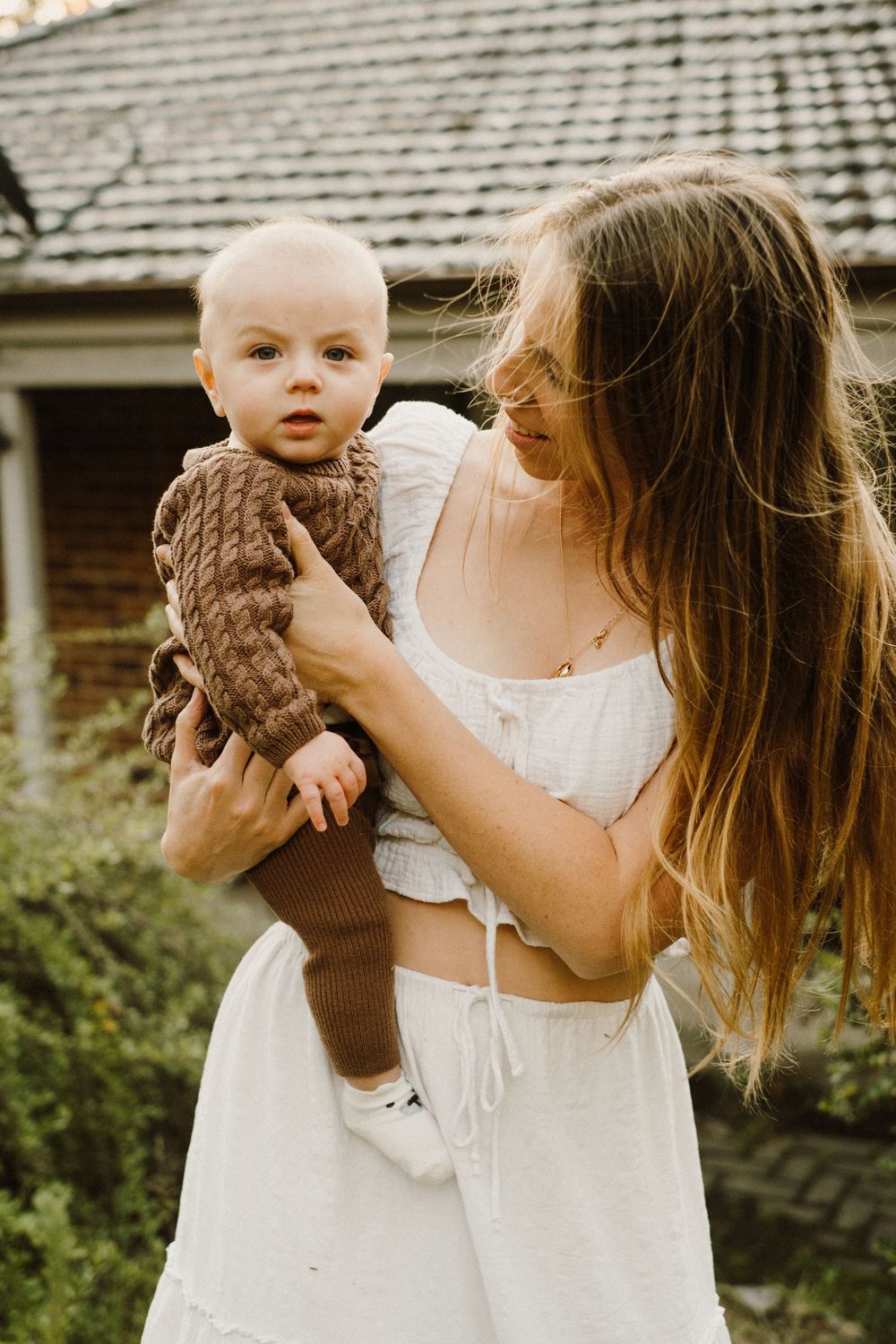 Candid outdoor portrait in white dress with brown knit accessory.