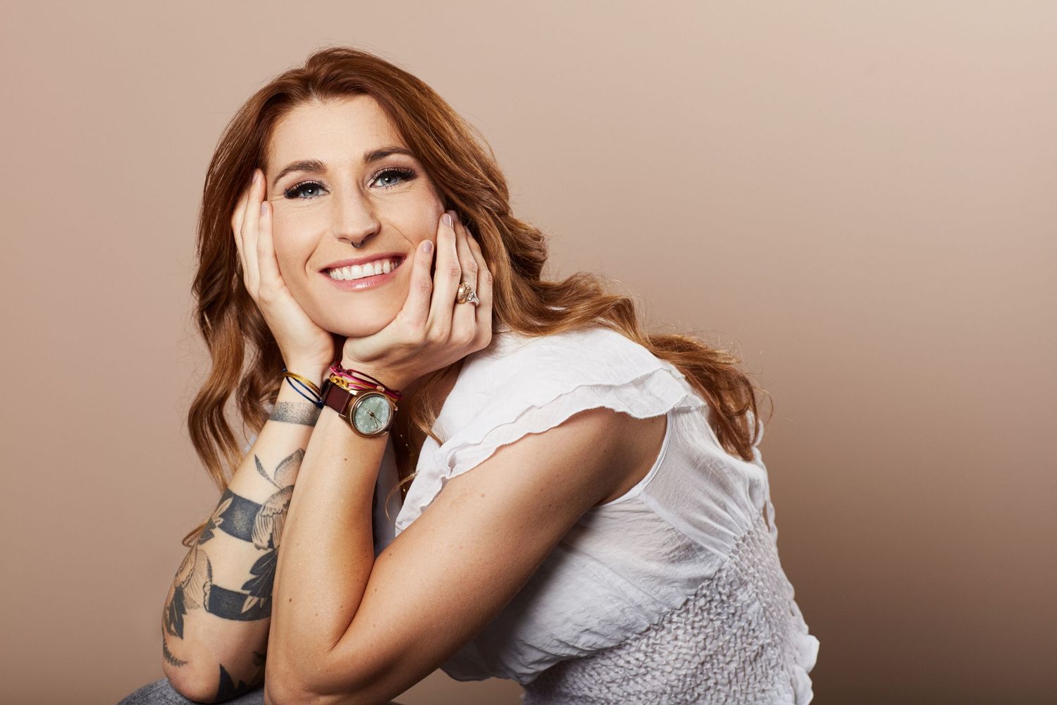 A woman sitting smiling with her hands on her face
