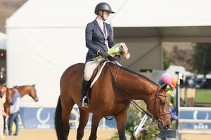 Horse and rider, holding bouquet with a winners medal around her neck