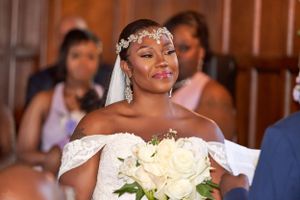 A radiant bride wearing a floral headpiece holds white roses during her ceremony.