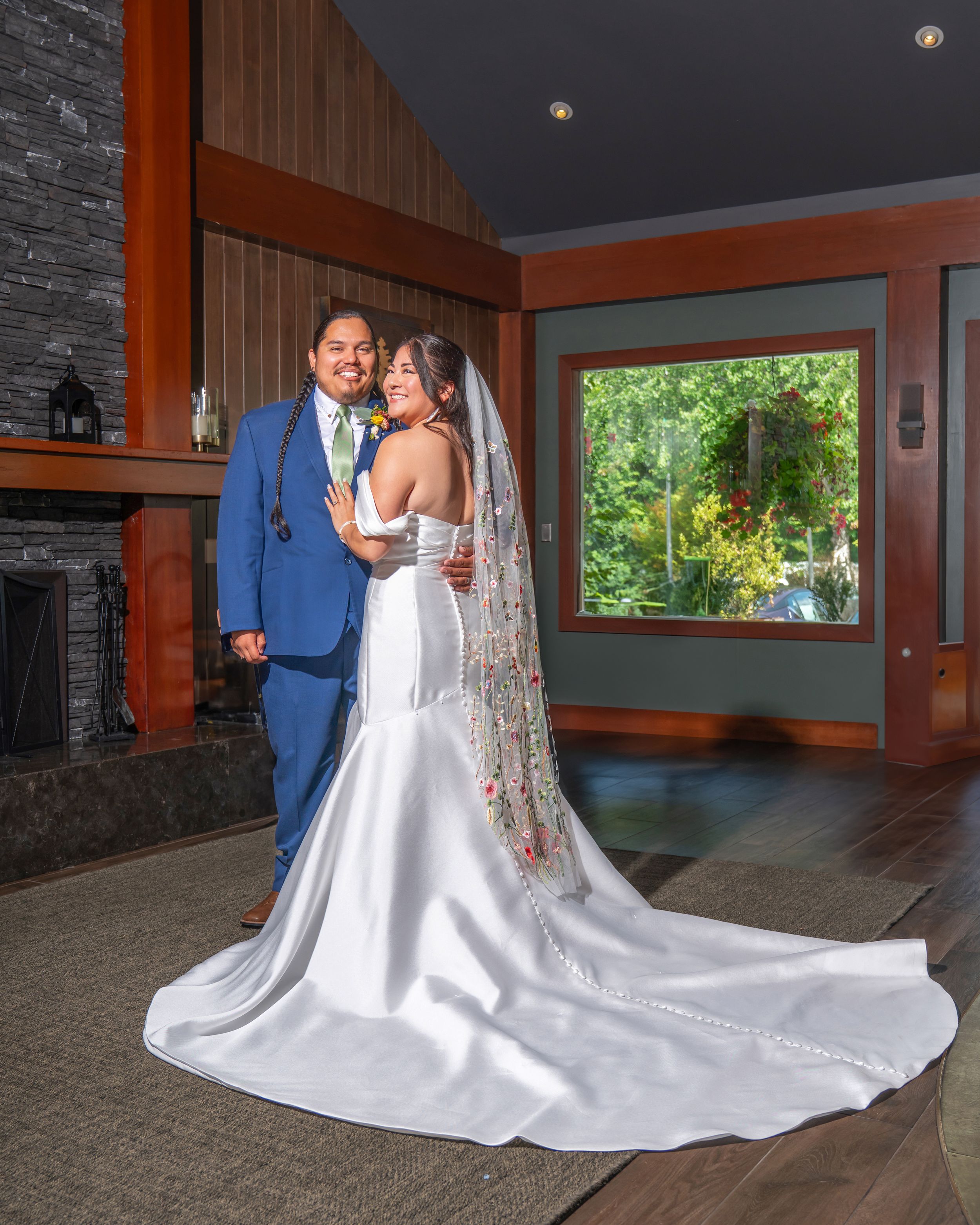 A couple in formal wedding attire dance together in an elegant venue with stone walls and wooden accents.