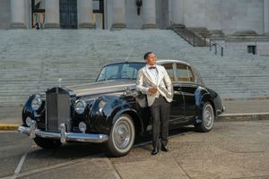 Vintage luxury cars parked in front of grand stone steps of a classic building for a wedding photo shoot.