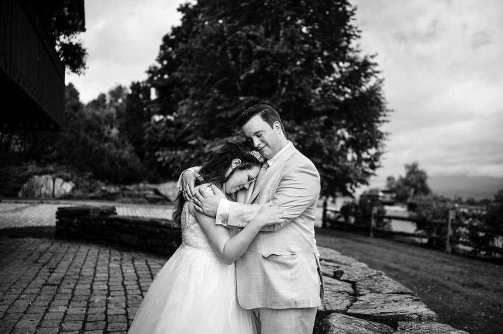 Bride and groom embracing tenderly in black and white wedding portrait outdoors.