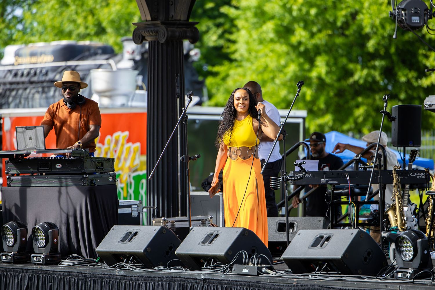 Professional audio equipment and instruments set up on an outdoor stage during a daytime event.