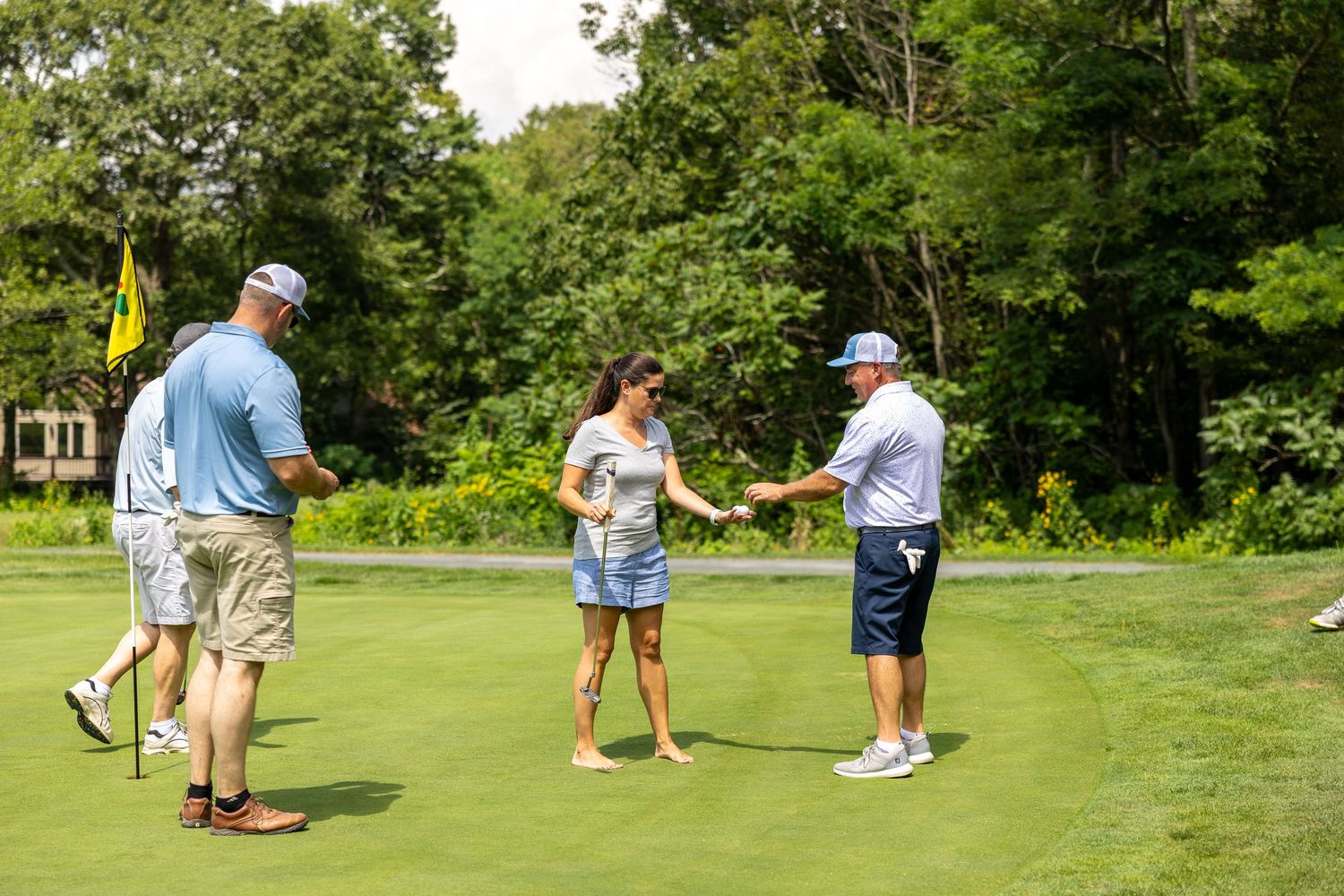 Golf course scene with players and equipment on sunny green fairway.