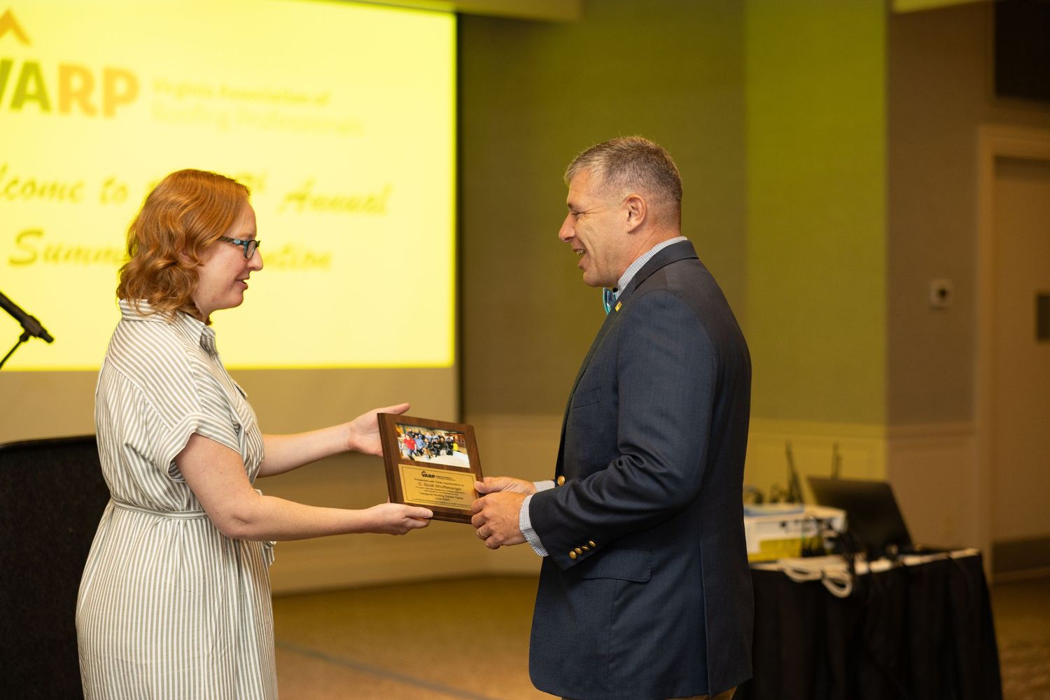 Business professionals exchanging awards and recognition at a corporate event ceremony.