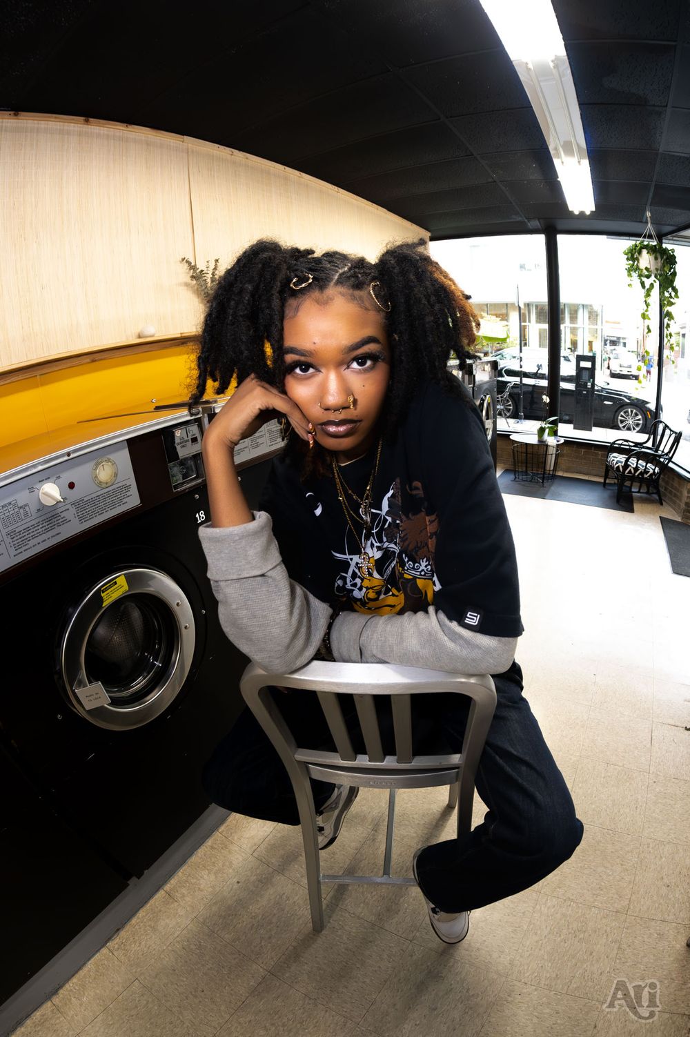 Person in casual wear poses on chair in laundromat with fisheye lens perspective.