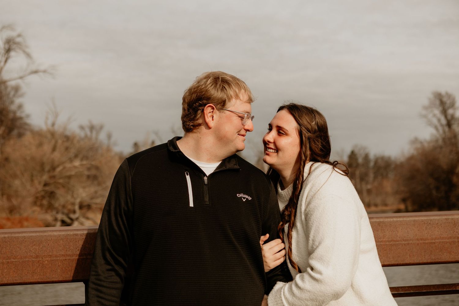 Intimate outdoor couple portrait sharing a tender moment on a wooden bench.