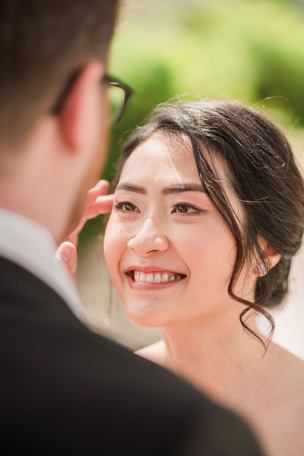 Close up of bride smiling joyfully during wedding ceremony outdoors.