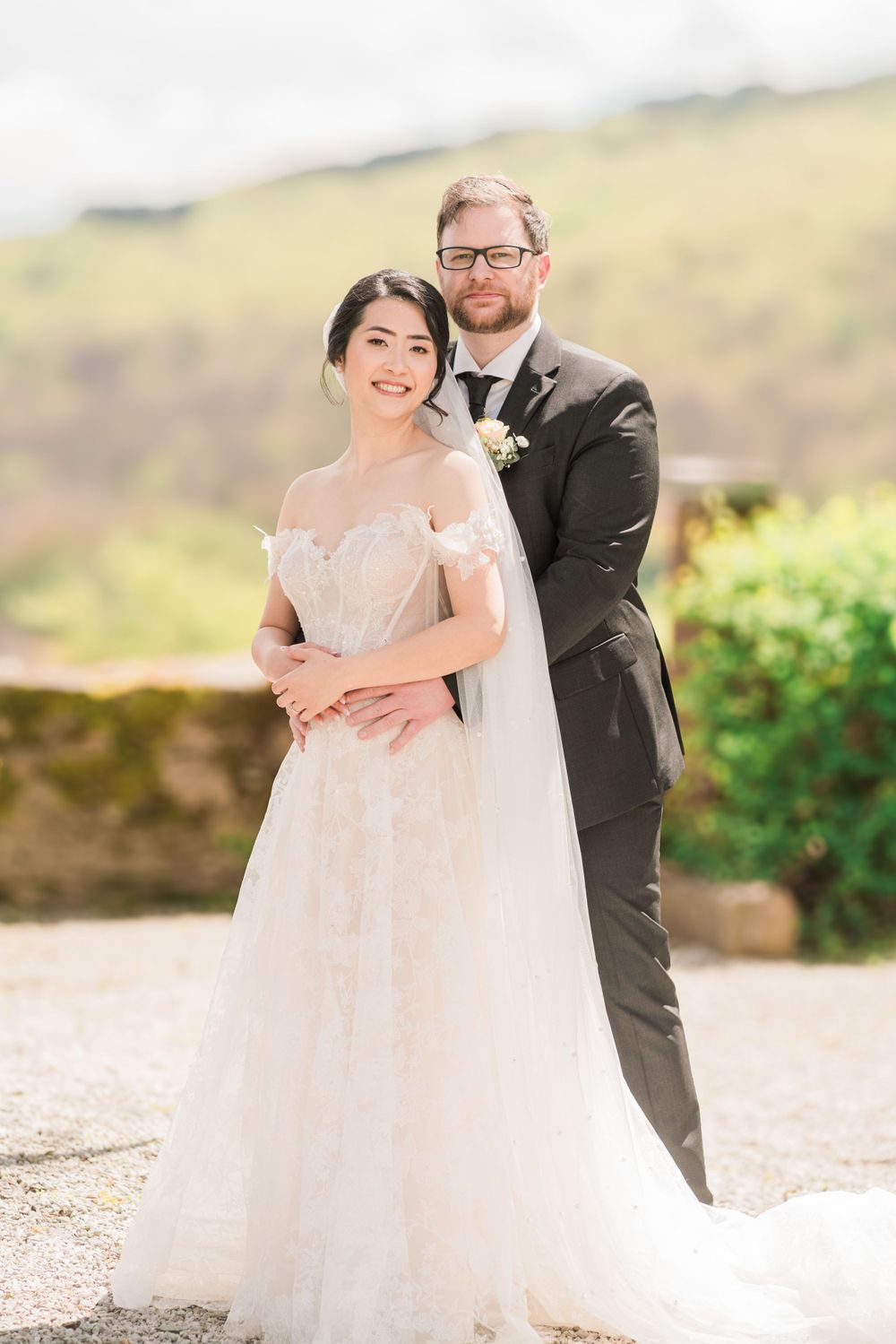 Classic wedding portrait of couple against scenic hillside background.