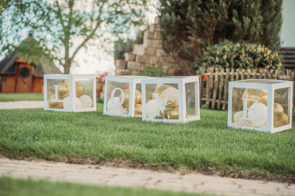 Decorative white lanterns with gold accents arranged on grass for outdoor wedding decor.