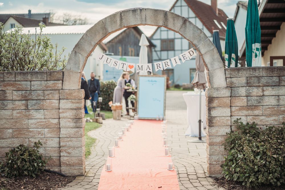 Stone archway entrance decorated with 'just married' banner and coral colored runner.