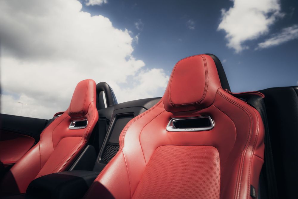 Red leather sports car seats with headrests against blue sky background. Mtlshutter photography