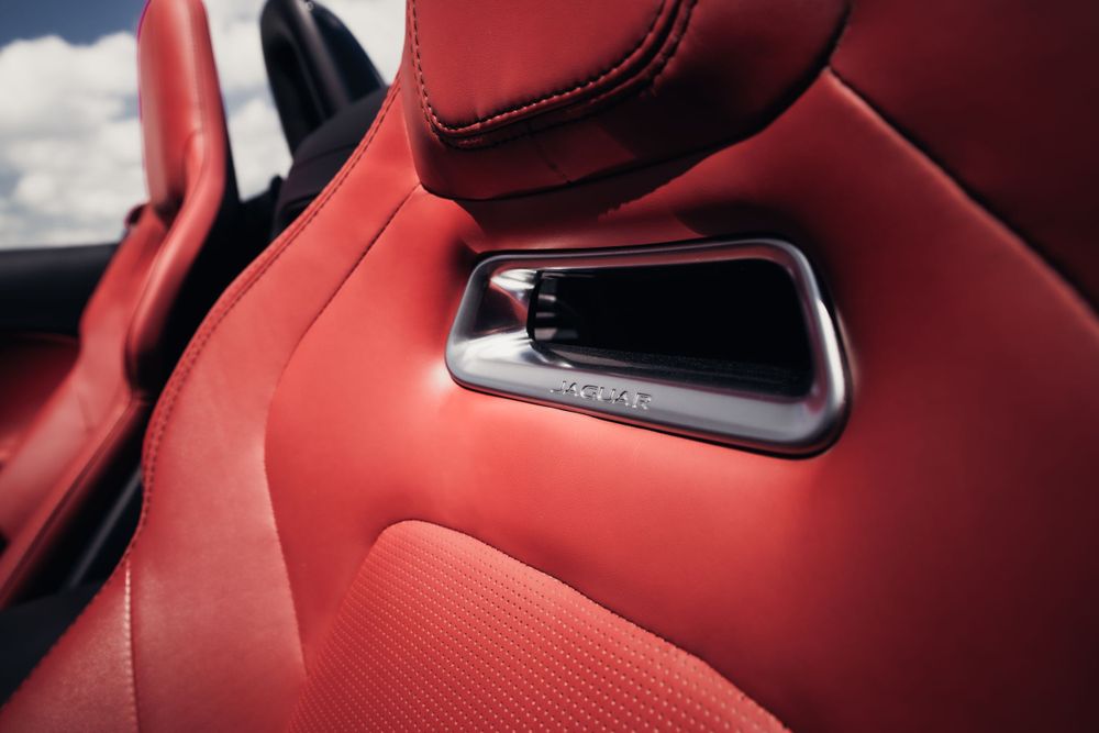 Close-up detail of red leather car seat with metal accent trim. Mtlshutter photography