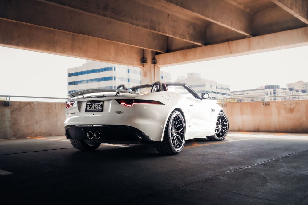 White Jaguar F-Type convertible with custom wheels parked in a covered parking structure. Mtlshutter photography