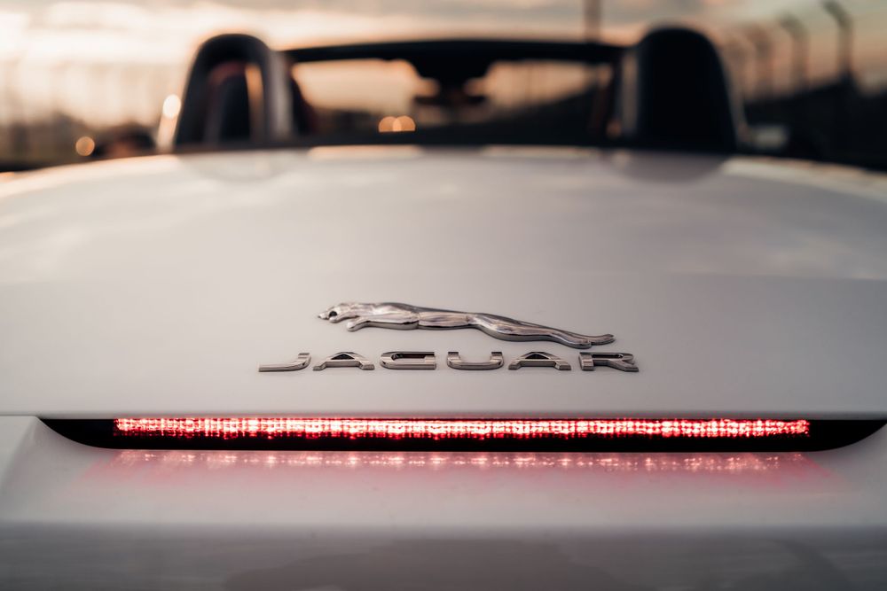 Close-up detail of Jaguar badge and brake light on white sports car. Mtlshutter photography