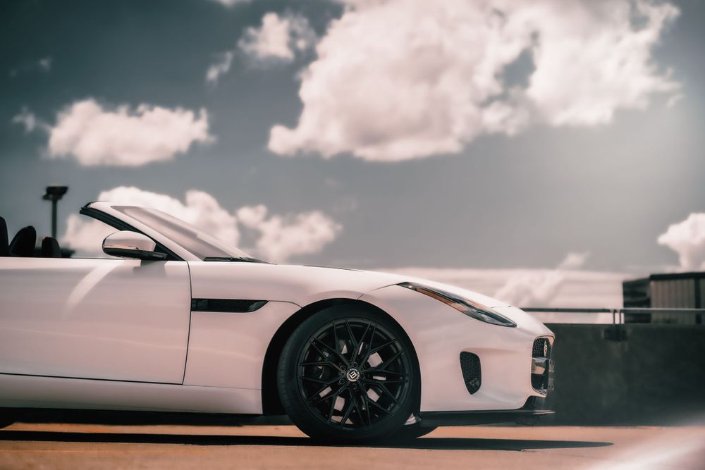 Side profile of white Jaguar F-Type convertible against cloudy sky. Mtlshutter photography