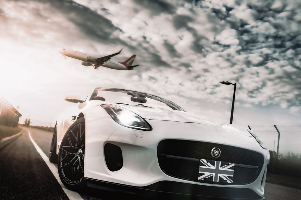 White Jaguar F-Type with Union Jack grille detail photographed with airplane in background. Mtlshutter photography