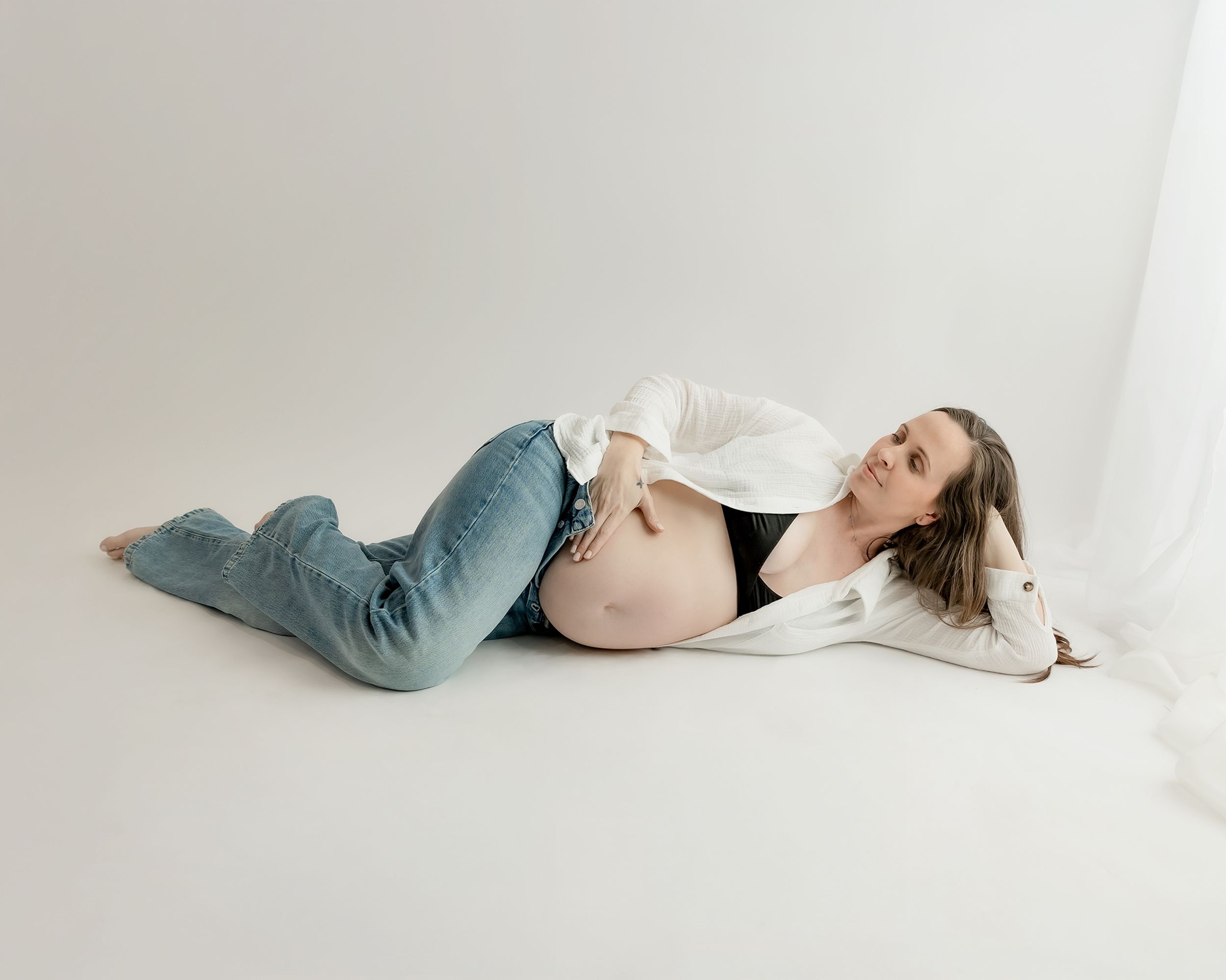 Pregnant woman laying by window during maternity session
