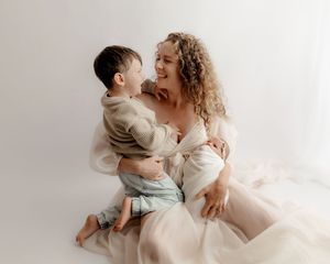 mother cuddling her new baby and sharing a sweet moment with the eldest child