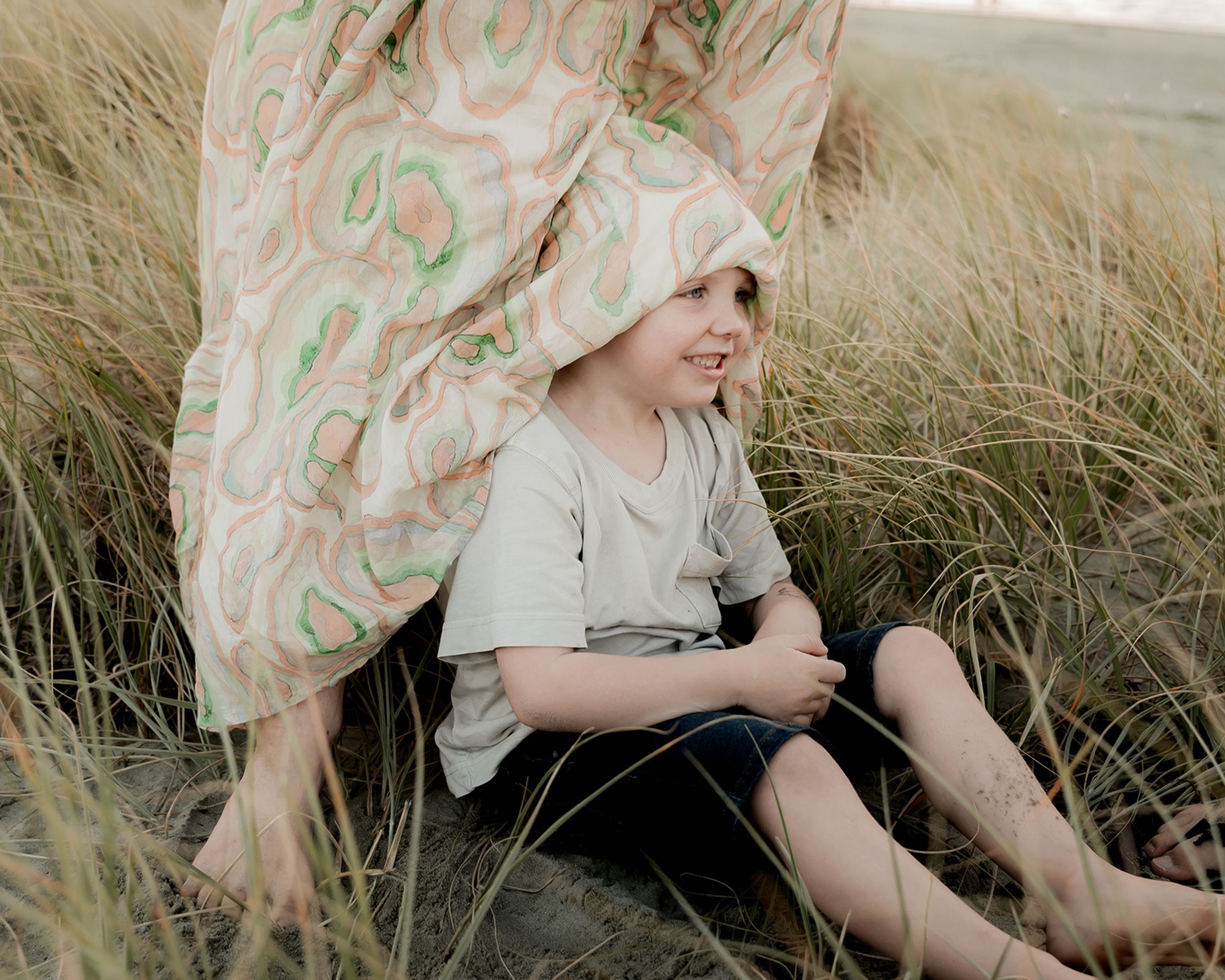 son hiding under his mothers dress playfully during a photo shoot