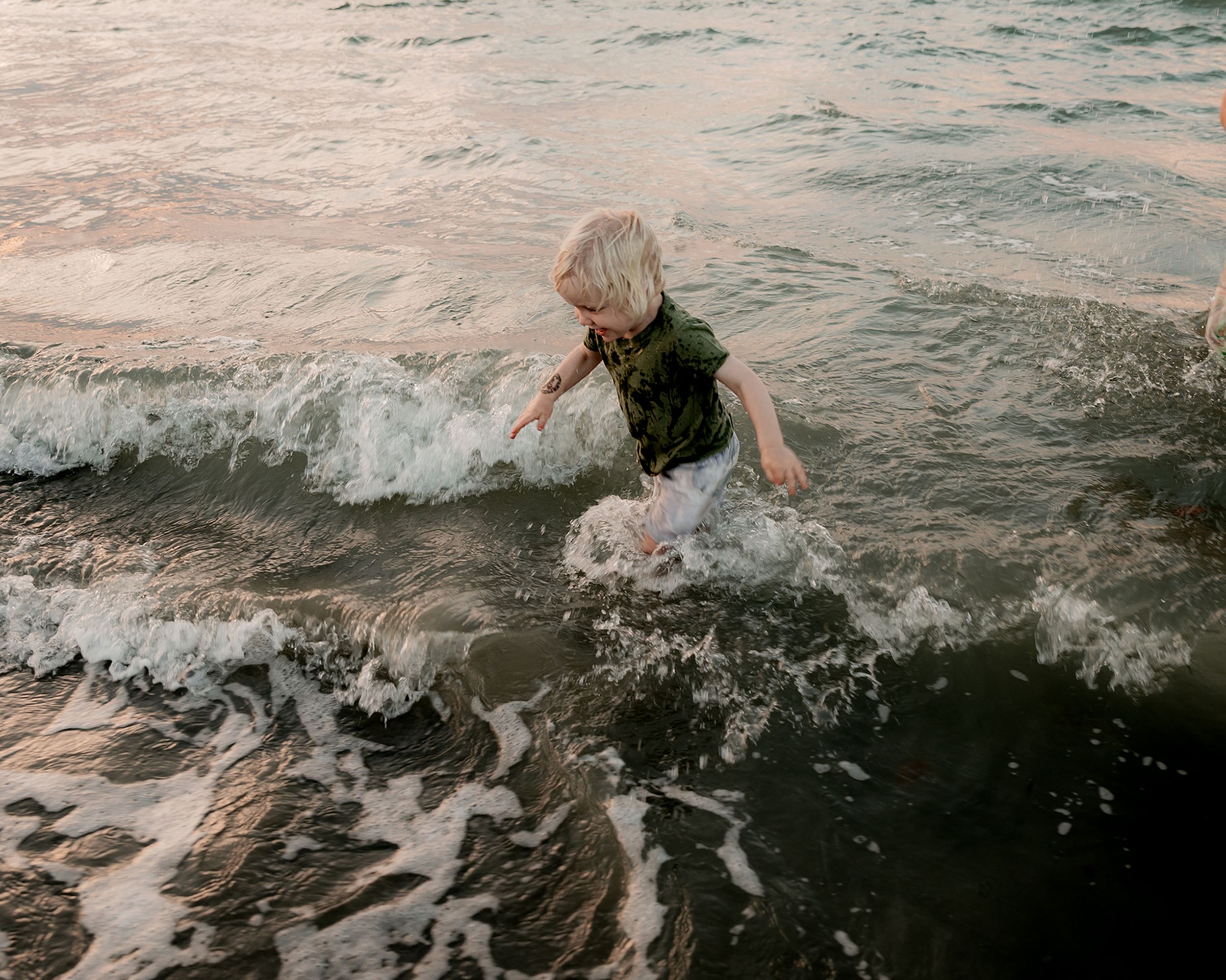 child playfully running through the ocean during a relaxed family session