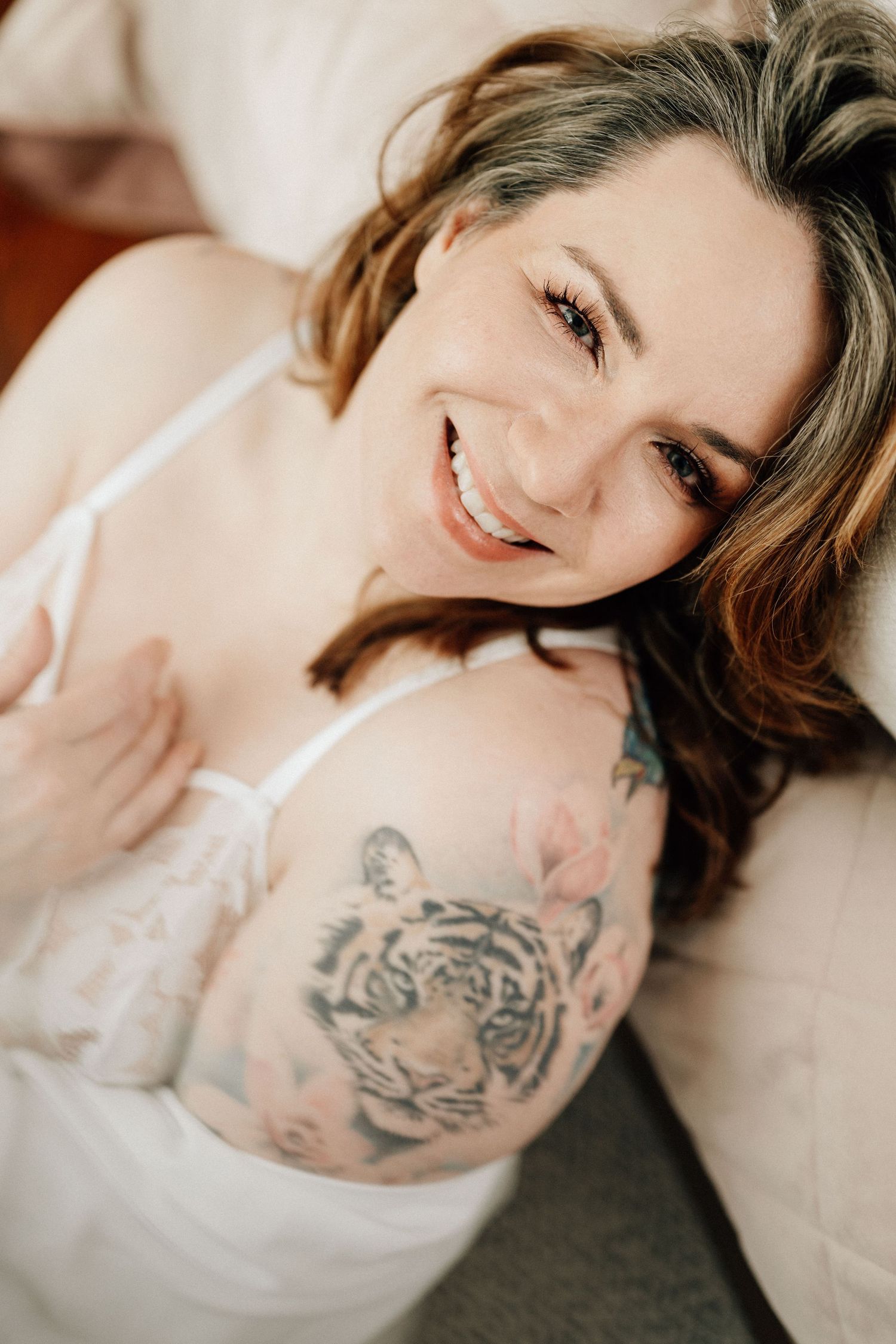 authentisch lächelnde Frau beim Boudoir Shooting im hellen, zarten Licht