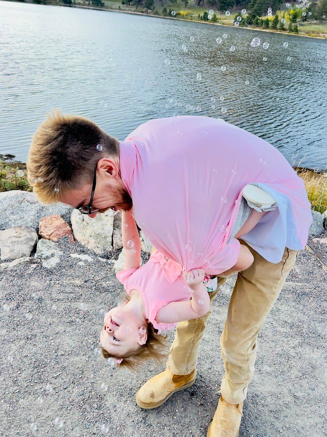 dad holding baby upside down laughing