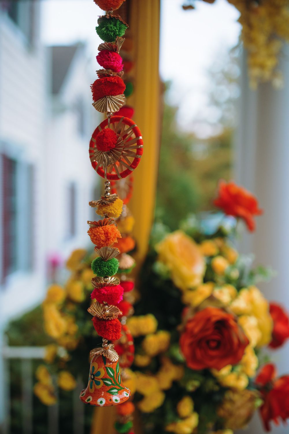 Vibrant red and orange floral garlands hang elegantly against a backdrop of yellow drapes at an Indian wedding.