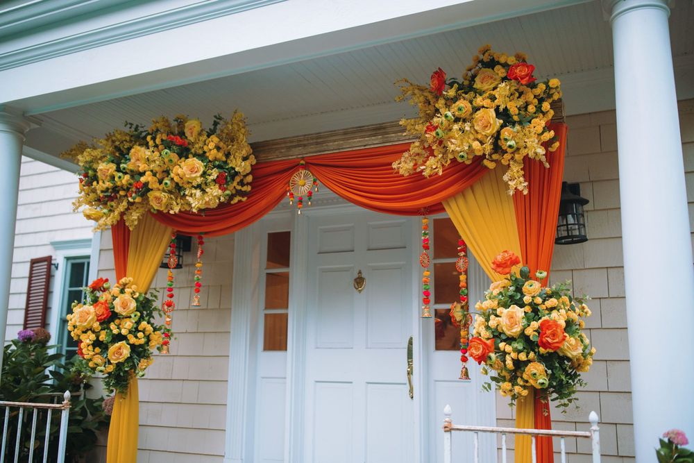 Outdoor venue decorated with yellow and orange floral arrangements and fabric drapes.