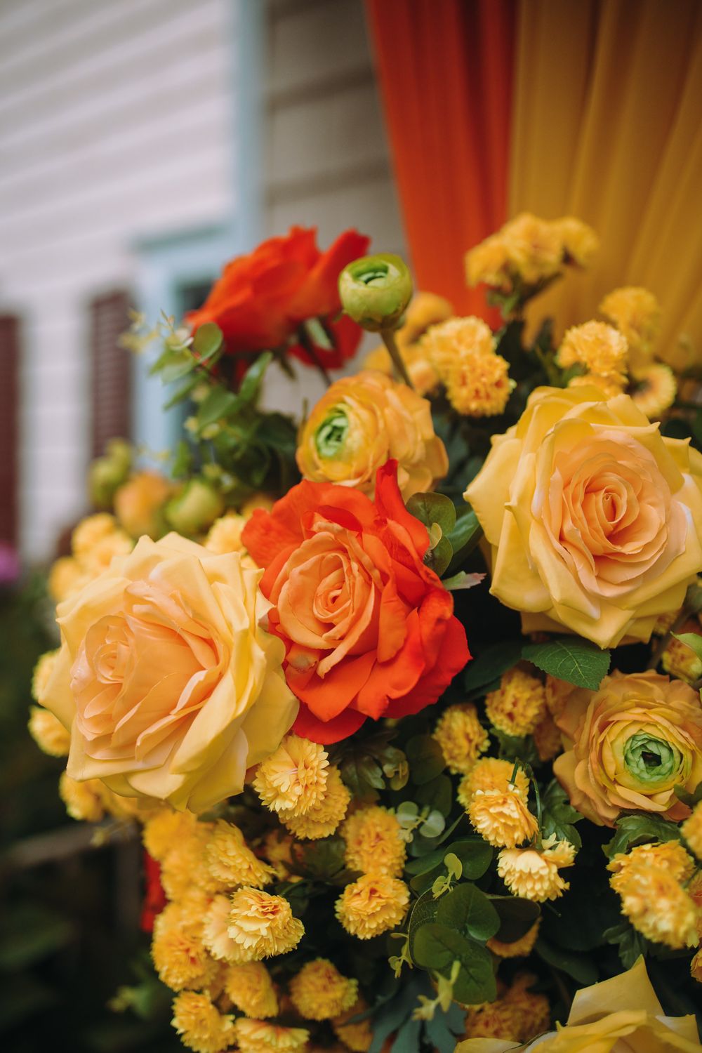 Close-up of yellow and orange rose flower arrangements with green accents.