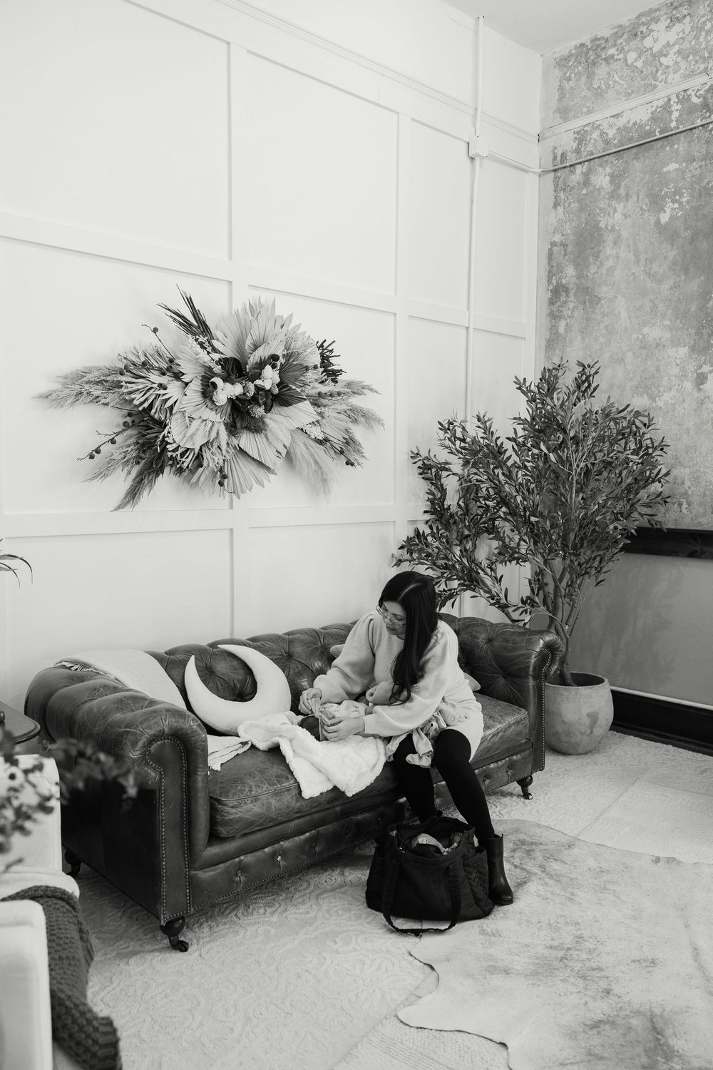 Black and white image of a room with scattered belongings and floral arrangements.