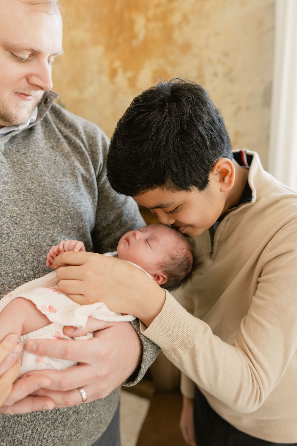 A series of intimate photos showing tender moments between parents and their newborn baby against a warm beige backdrop.