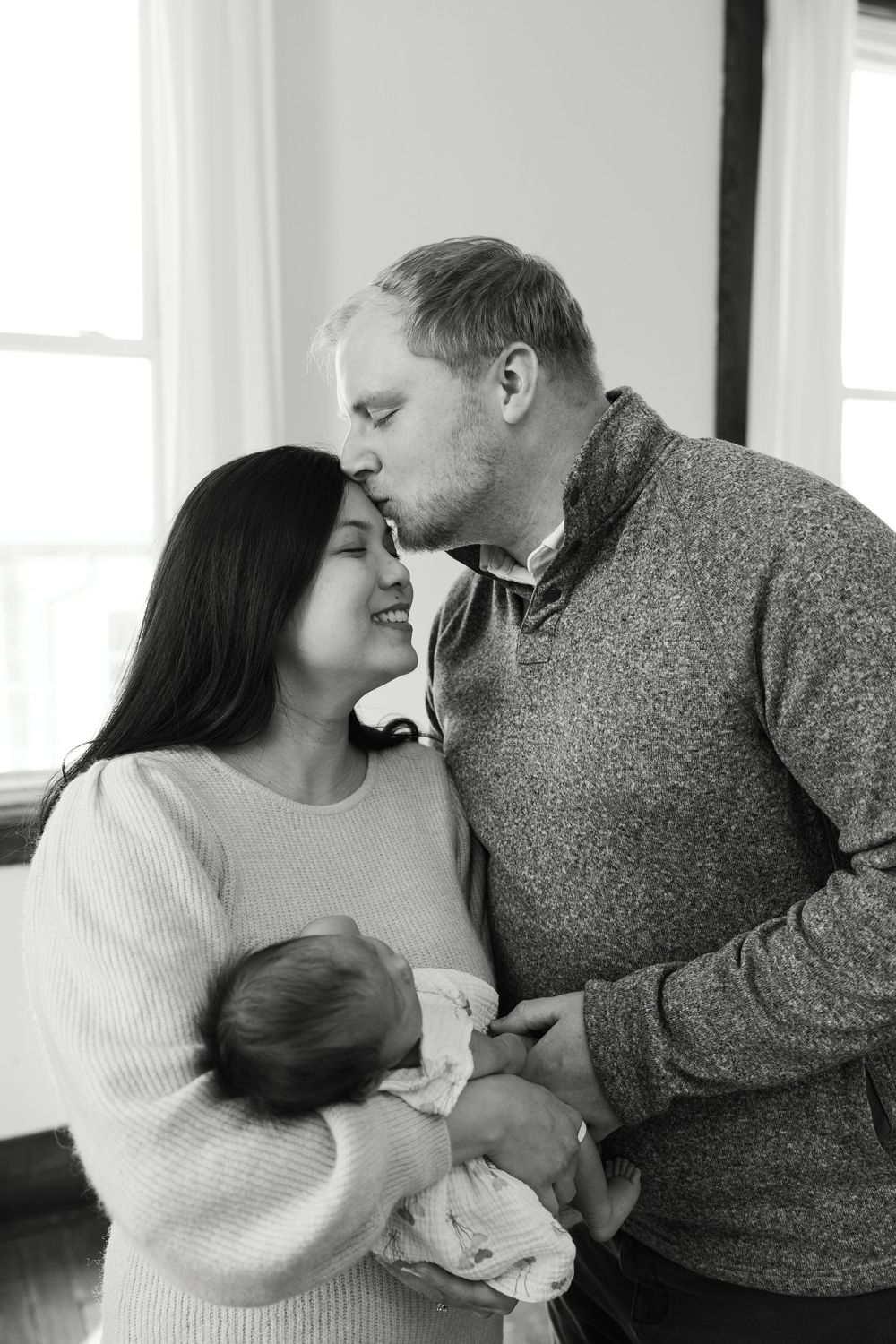 Intimate family moment with newborn baby in black and white photography.
