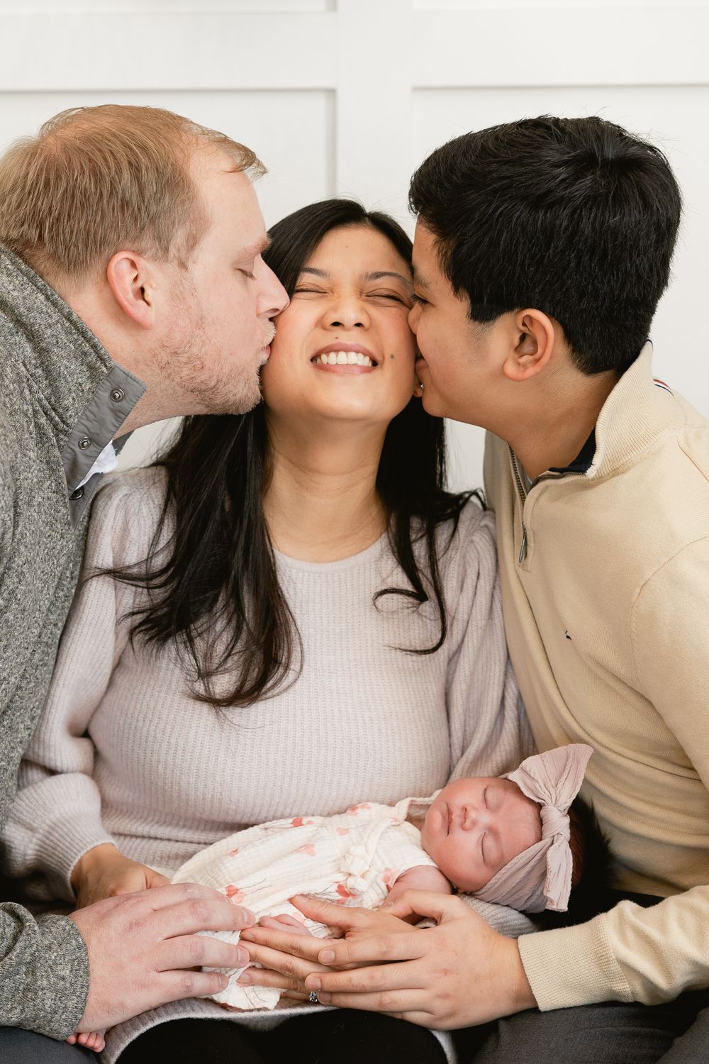 A precious newborn baby is lovingly cradled while wearing a pink outfit.